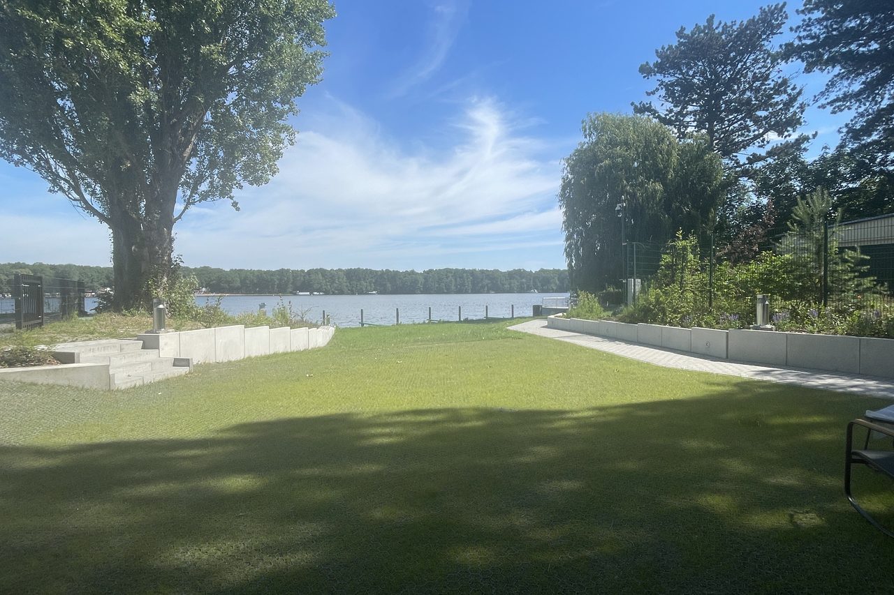Rasenfläche des Hotels, die bis an das Ufer reicht, dahinter der See